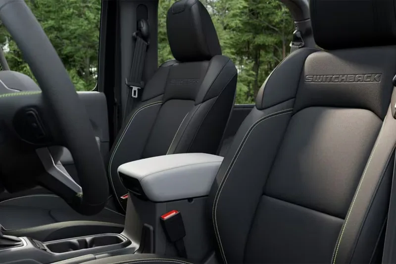 Sièges de voiture noirs avec détails verts, intérieur moderne avec arbres en arrière-plan.