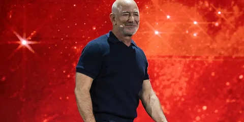 Homme chauve souriant sur fond rouge scintillant.
