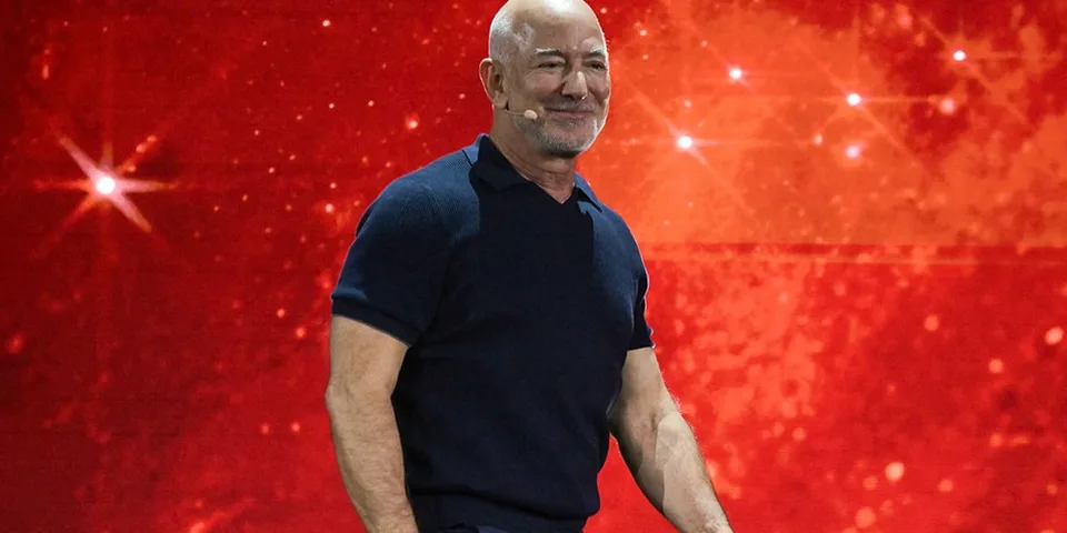 Homme chauve souriant sur fond rouge scintillant.