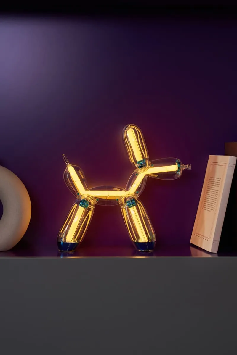 Lampe design en forme de ballon chien, lumière chaude, fond violet.