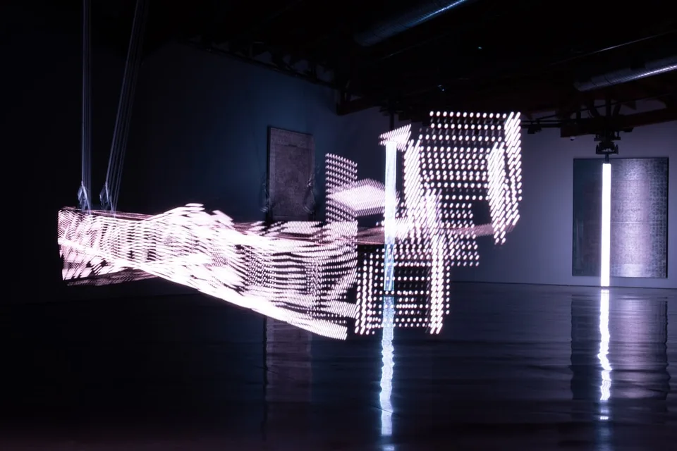 Installation lumineuse abstraite dans une galerie sombre.