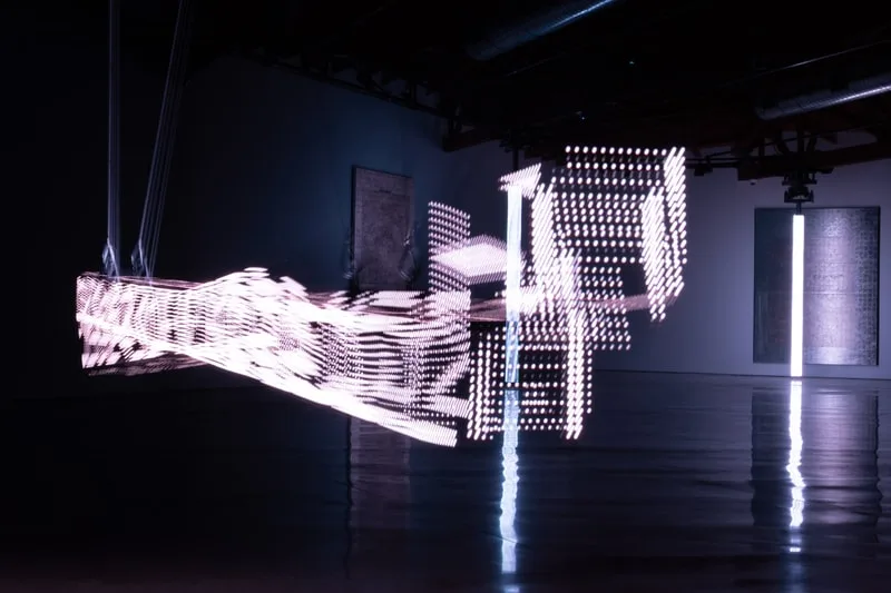 Installation artistique lumineuse abstraite dans une galerie sombre.