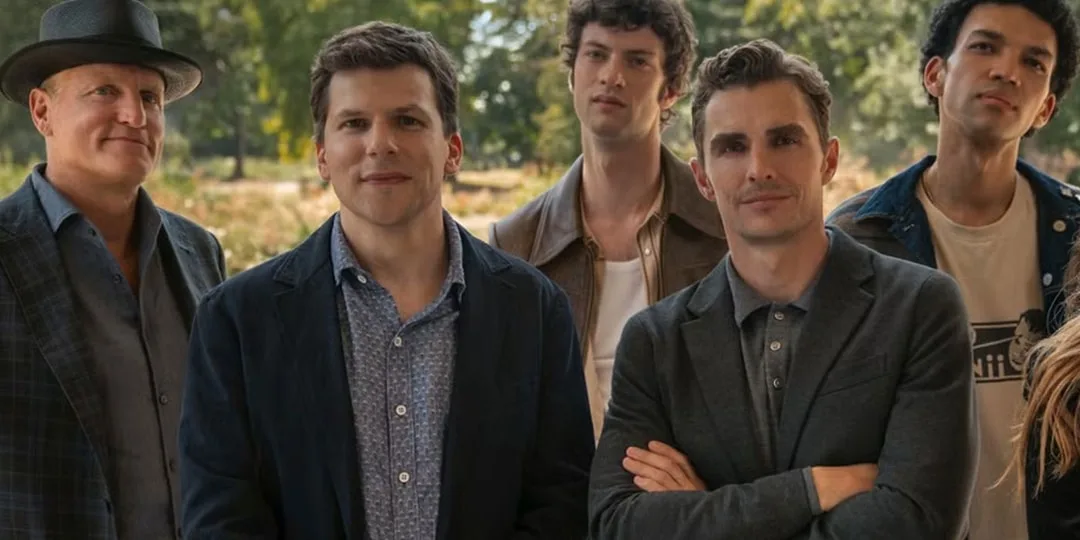 Cinq hommes posent ensemble dans un parc verdoyant.