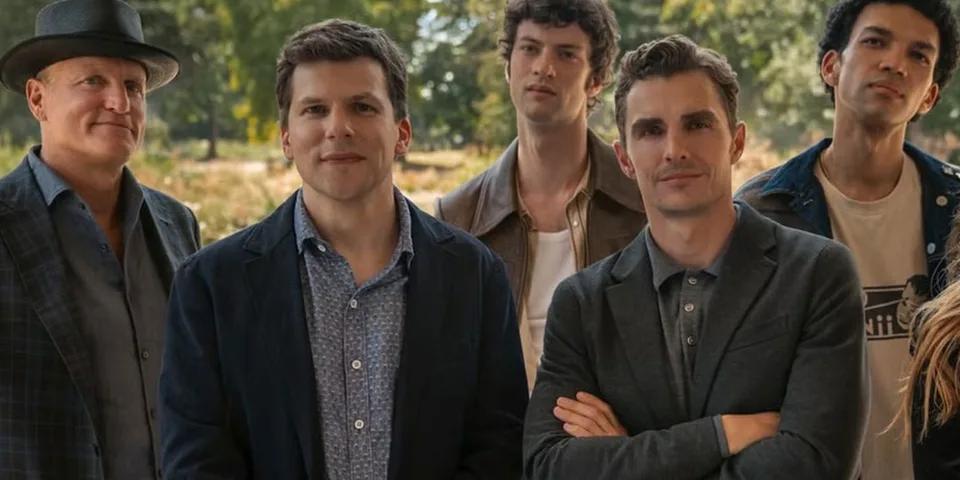 Cinq hommes posent ensemble dans un parc verdoyant.