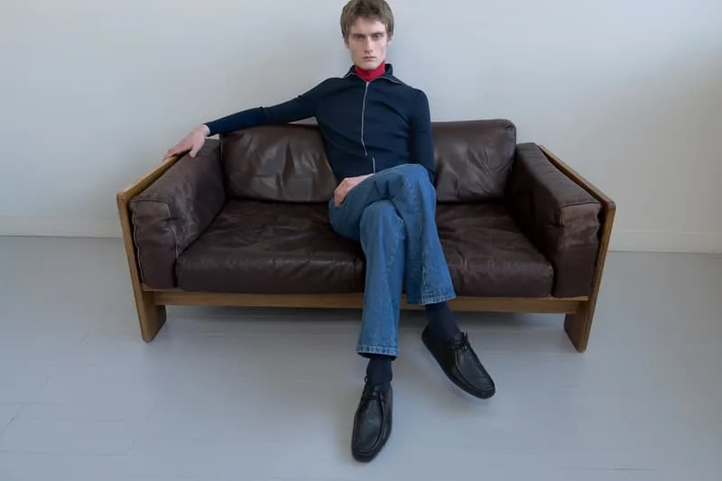 Homme assis sur un canapé en cuir marron, pose détendue.
