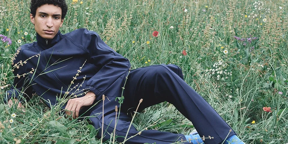Un homme en tenue sombre est allongé dans un champ de fleurs sauvages.