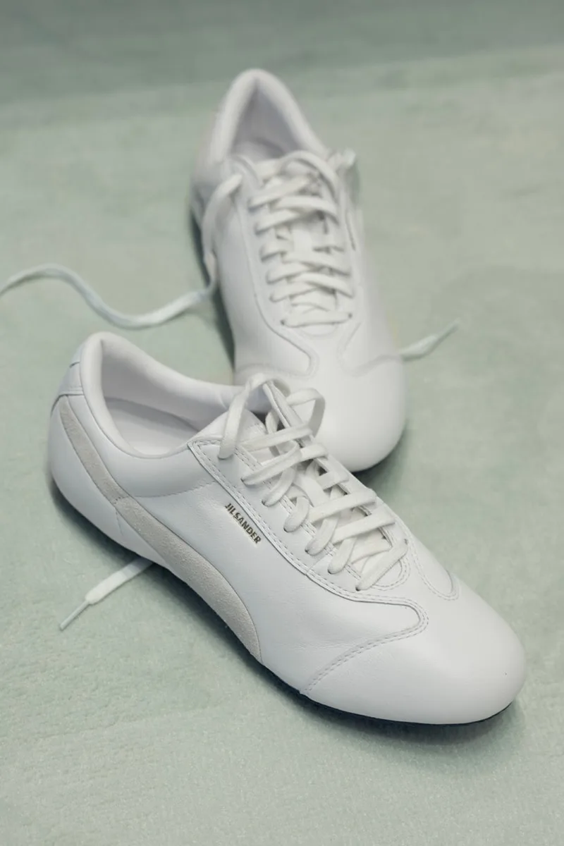 Chaussures blanches avec lacets sur fond vert clair.