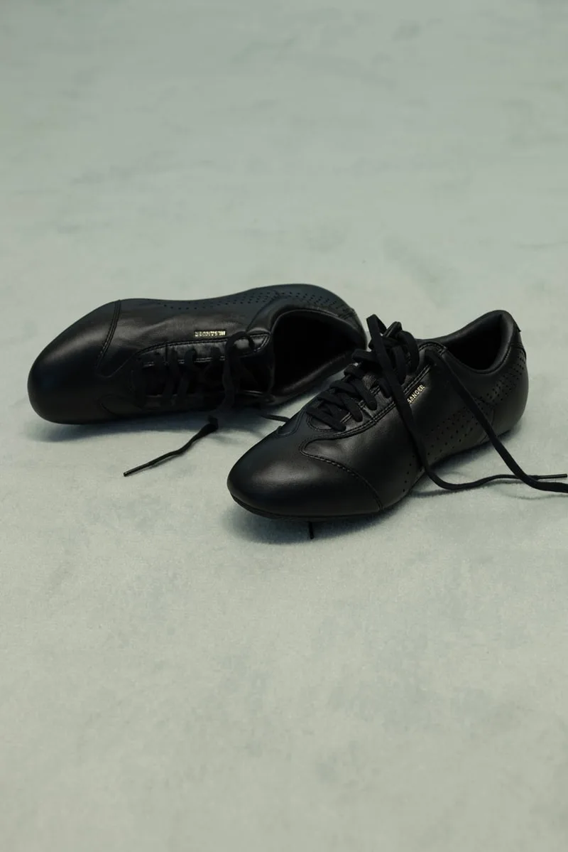 Chaussures noires avec lacets sur un sol clair.