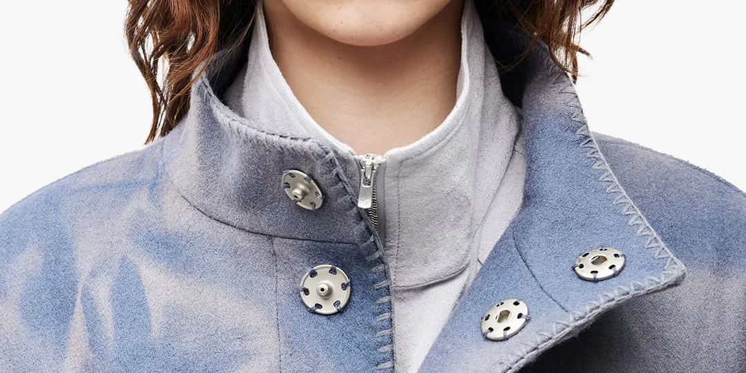 Détail d'une veste bleue avec boutons argentés.