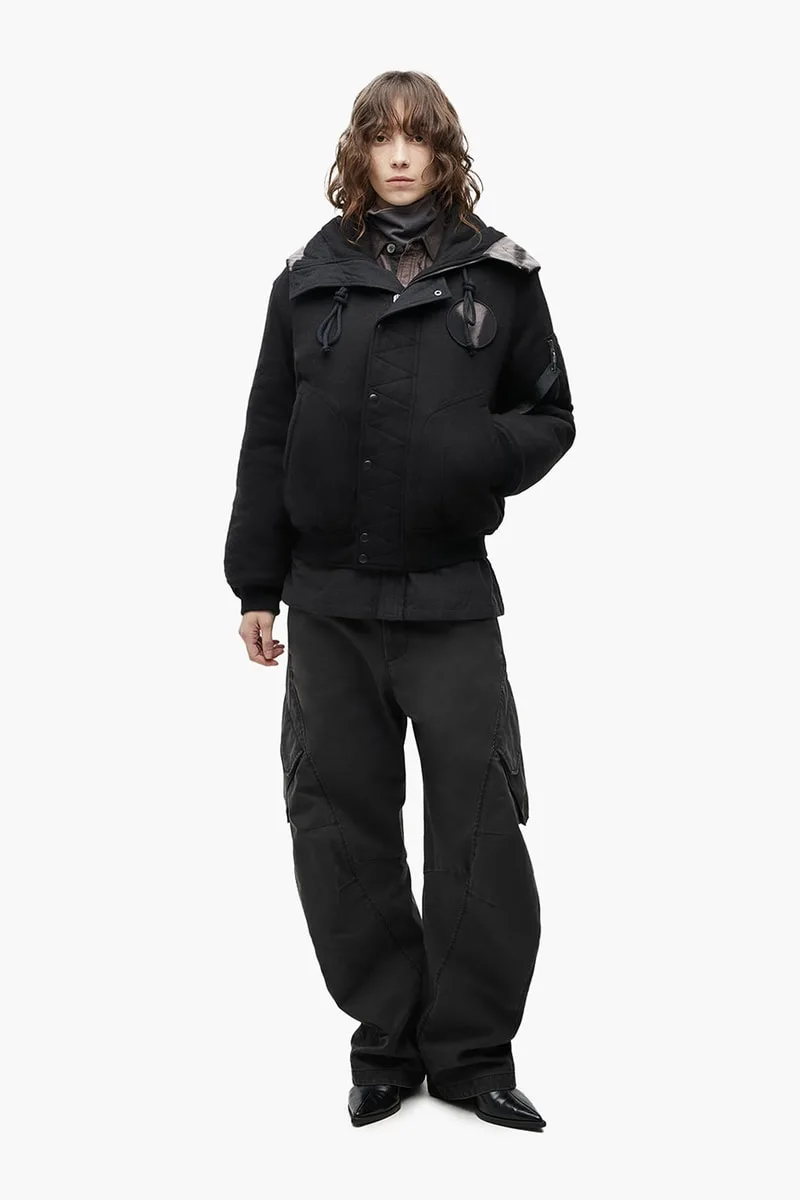Personne habillée en noir avec veste et pantalon larges.