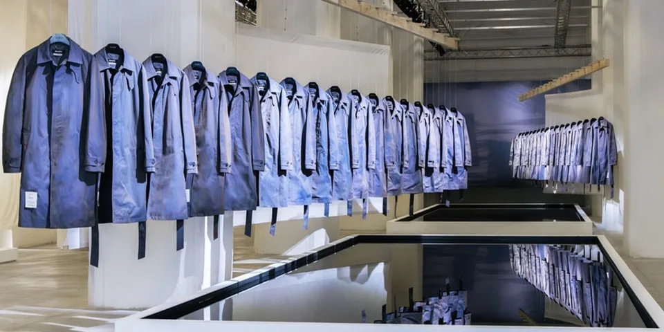 Rangée de manteaux bleus suspendus dans une salle d'exposition moderne.