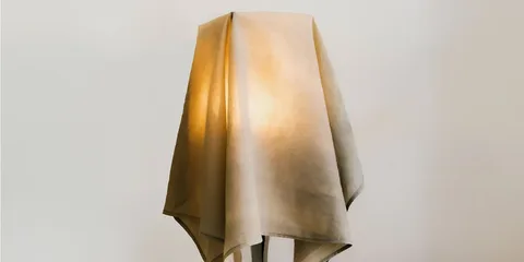 Lampadaire couvert d'un tissu beige laissant passer la lumière.