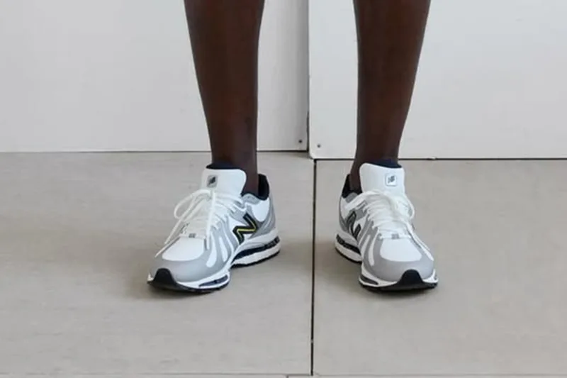 Homme portant des baskets blanches modernes sur un sol clair.