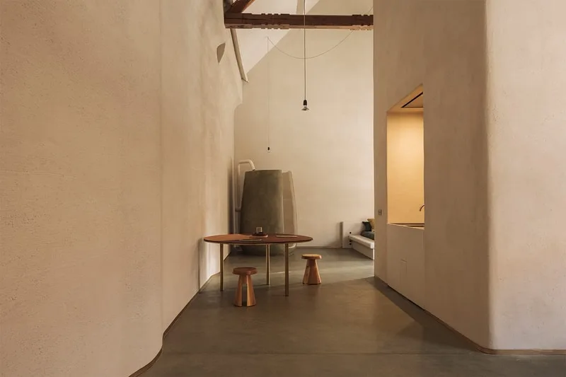 Intérieur minimaliste avec table et tabourets, murs beiges.