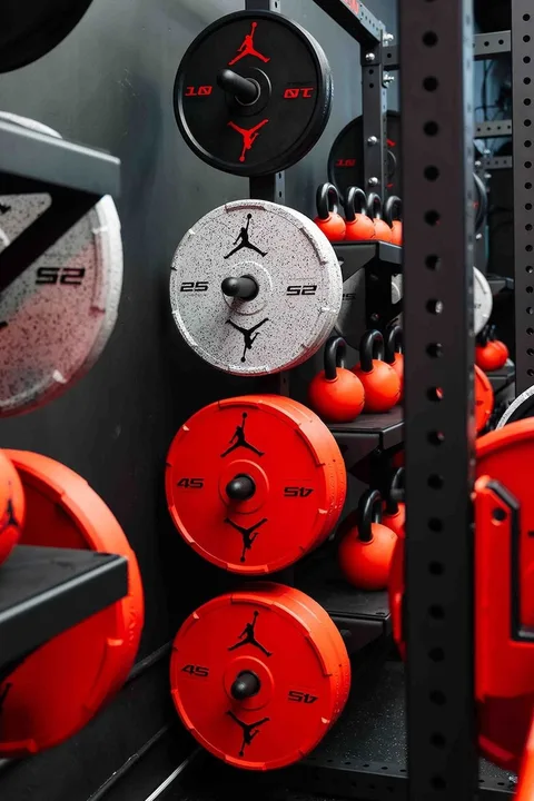 Poids et kettlebells noirs et rouges avec logo dans salle de sport