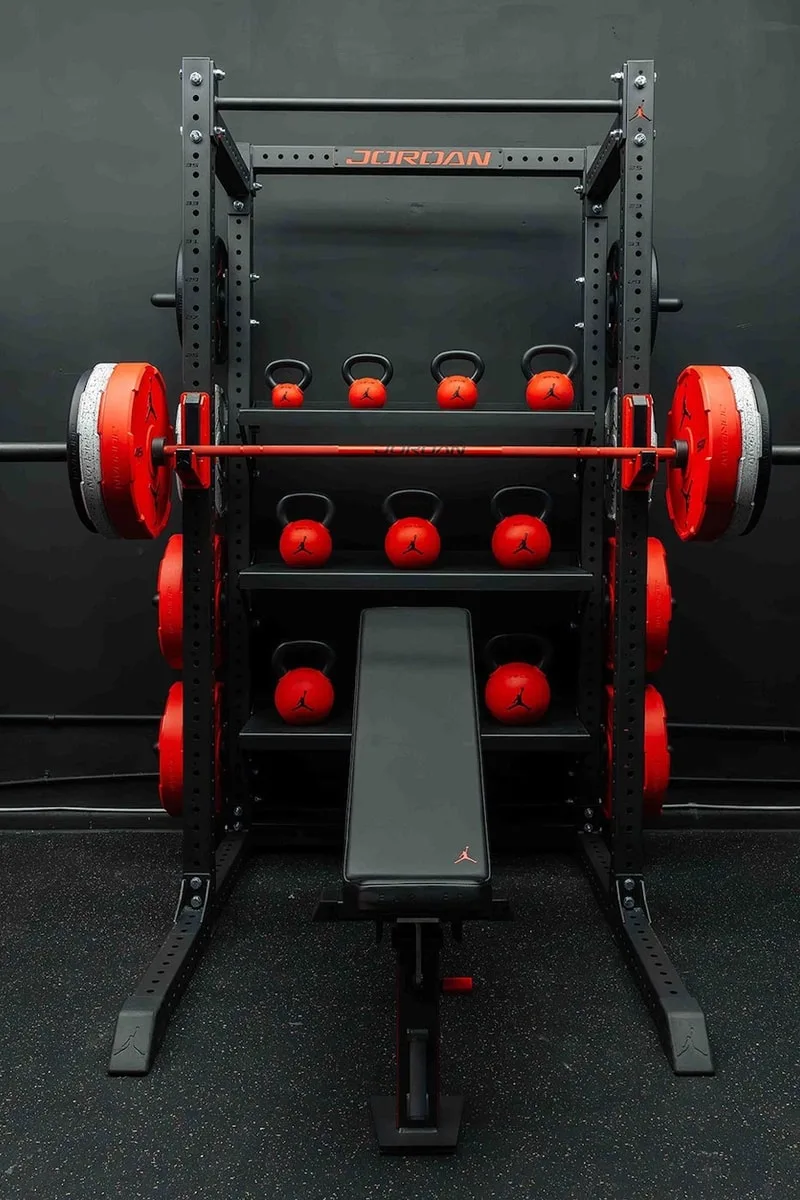 Équipement de gym avec poids rouges et banc de musculation.