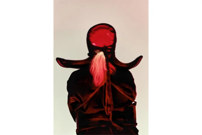 Personnage en capuche et manteau rouges, dos à la caméra.