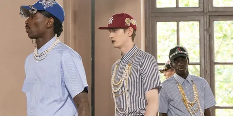 Des mannequins défilent avec des chapeaux et des colliers extravagants.