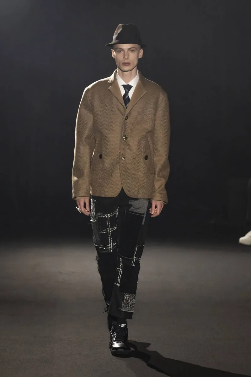Personne défile en tenue chic et à la mode sur une scène sombre.