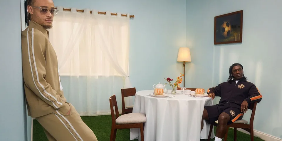 Deux hommes posant dans une pièce avec table et chaise.