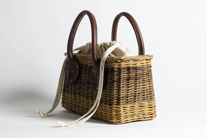 Panier en osier avec poignées et doublure en tissu blanc.
