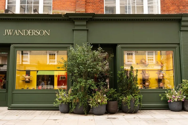 Magasin JW Anderson avec devanture verte et plantes en pots.