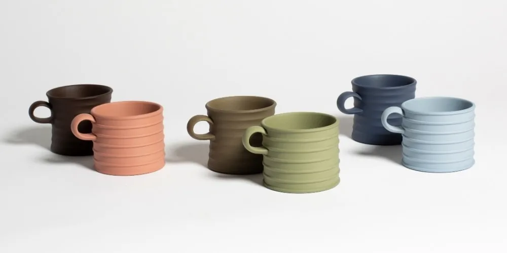 Six tasses de différentes couleurs sur fond blanc.