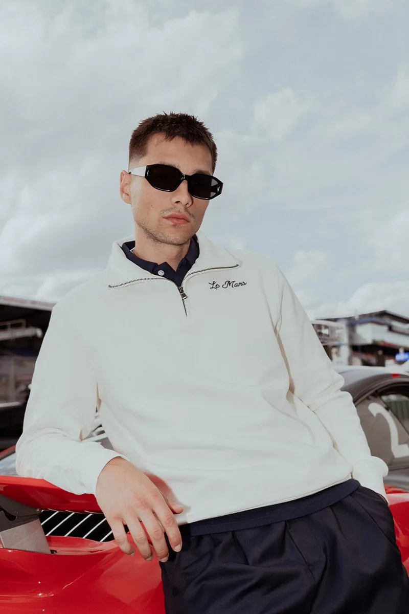 Homme en lunettes de soleil posant devant une voiture rouge