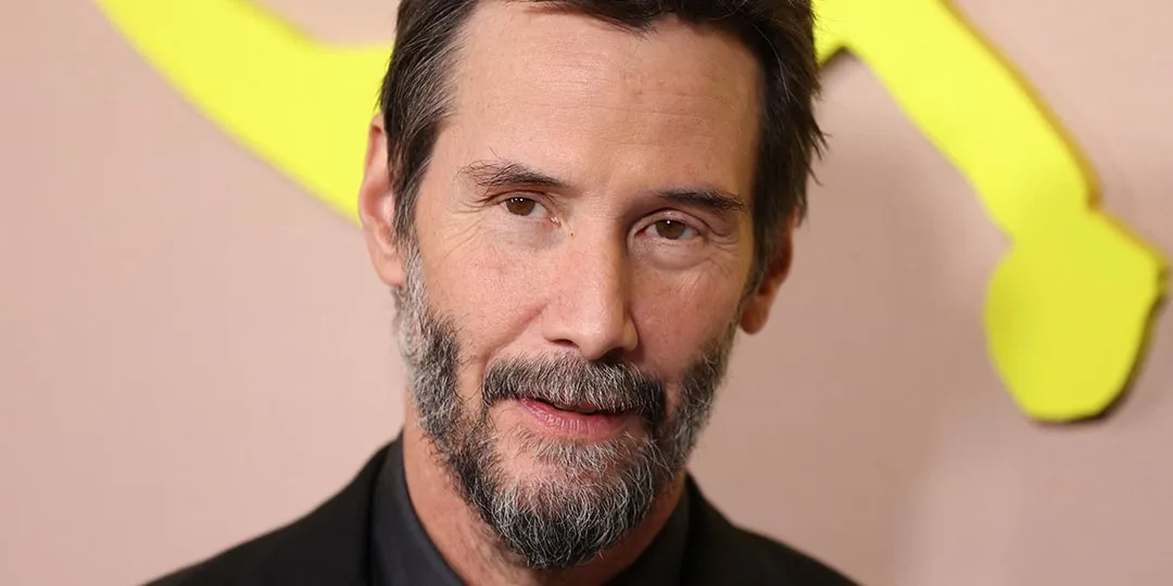 Portrait de Keanu Reeves barbu devant un fond rose et jaune