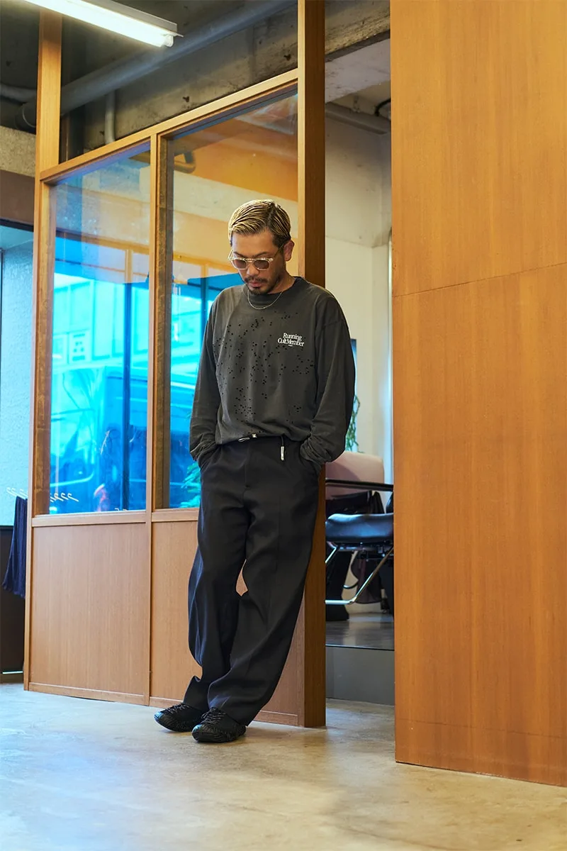Homme debout dans un espace intérieur avec tenue décontractée et lunettes.