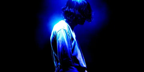 Silhouette d’une personne éclairée par une lumière bleue dans l’obscurité