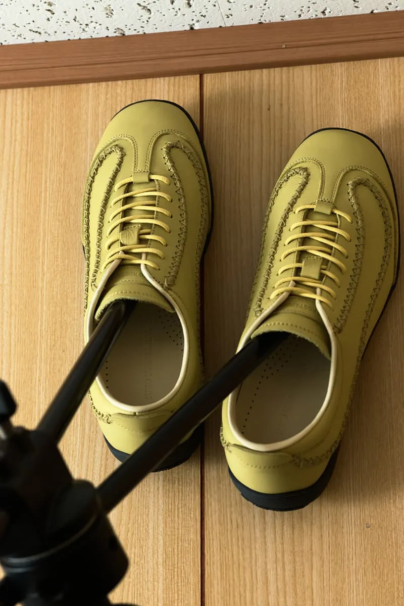 Paire de chaussures jaunes sur le sol avec un trépied.