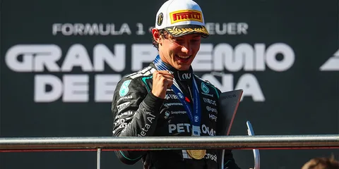Pilote F1 célèbre sur le podium avec médaille et trophée.