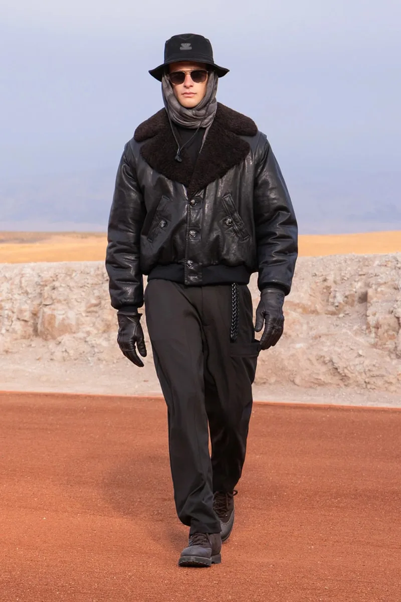 Homme en manteau noir sur une piste, look hivernal élégant.