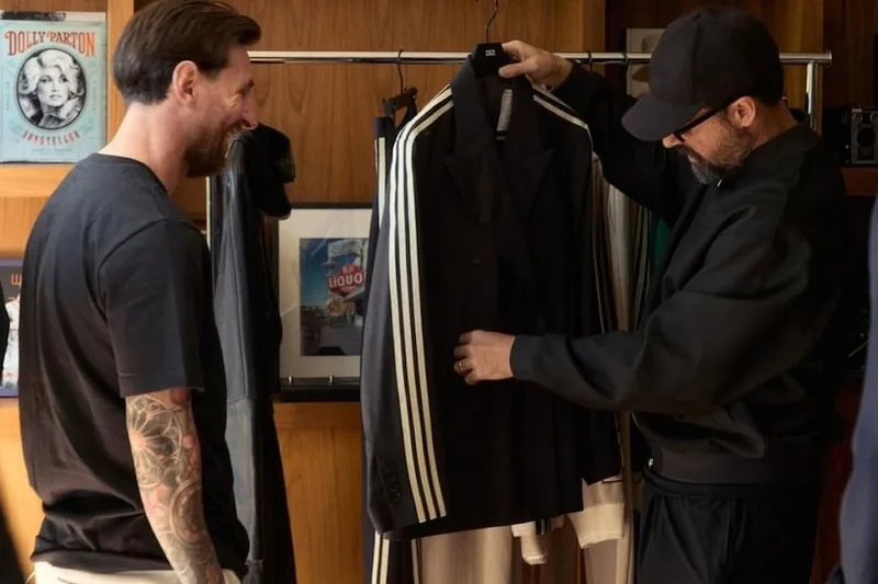 Deux hommes regardent un costume noir avec des bandes blanches.