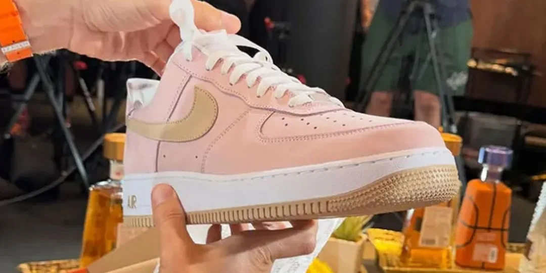Main tenant une chaussure rose avec logo Nike.