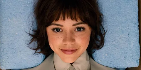 Femme souriante allongée sur une surface bleue.