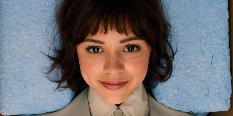 Femme souriante allongée sur une surface bleue.