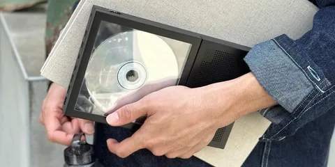 Personne tenant un lecteur CD portable et des dossiers