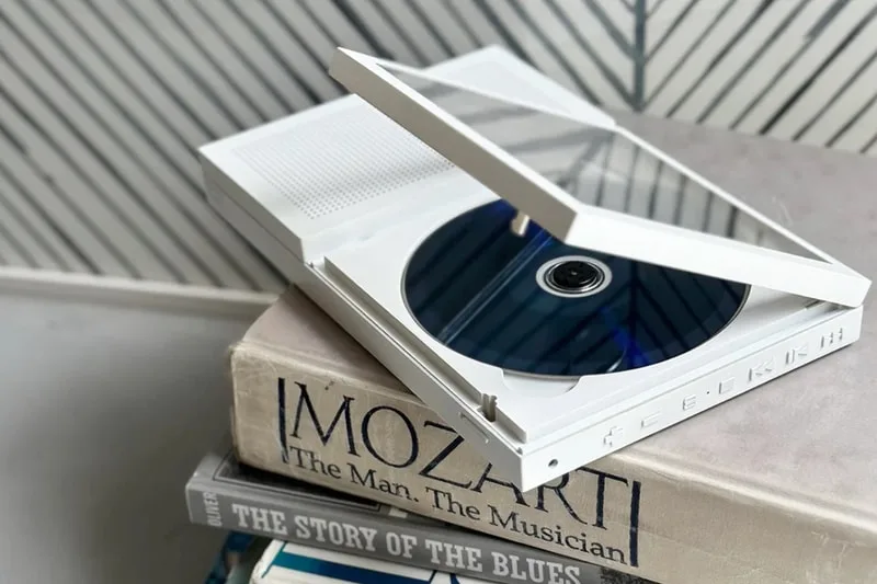 Lecteur CD transparent sur des livres avec motif en arrière-plan.
