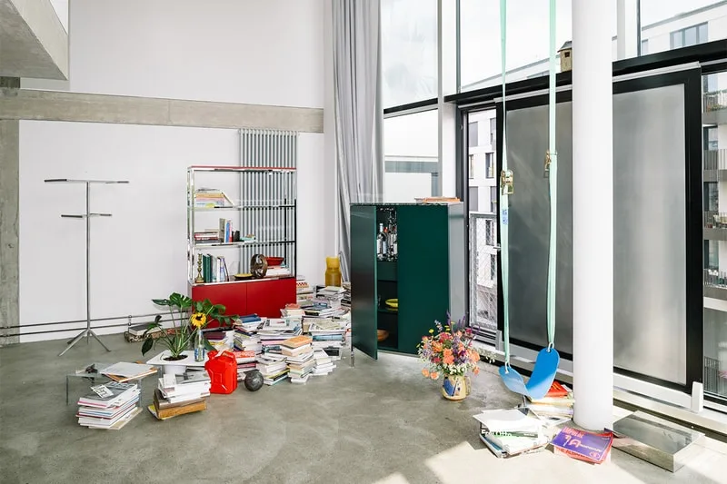 Intérieur moderne avec livres, chaise suspendue et fleurs.