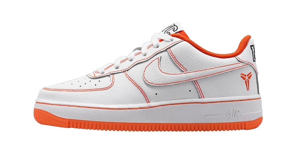 Chaussure de sport blanche avec accents orange et logo Nike, vue de côté gauche.