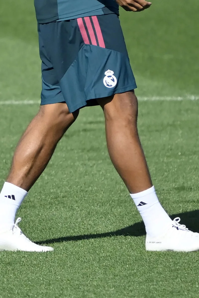 Joueur de foot portant un short d'entraînement brun et des chaussettes blanches.