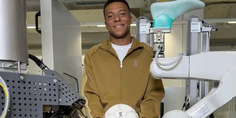 Homme avec un ballon de football et des machines robotiques.