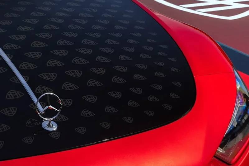 Voiture rouge avec emblème Mercedes et motifs Maybach sur le toit.