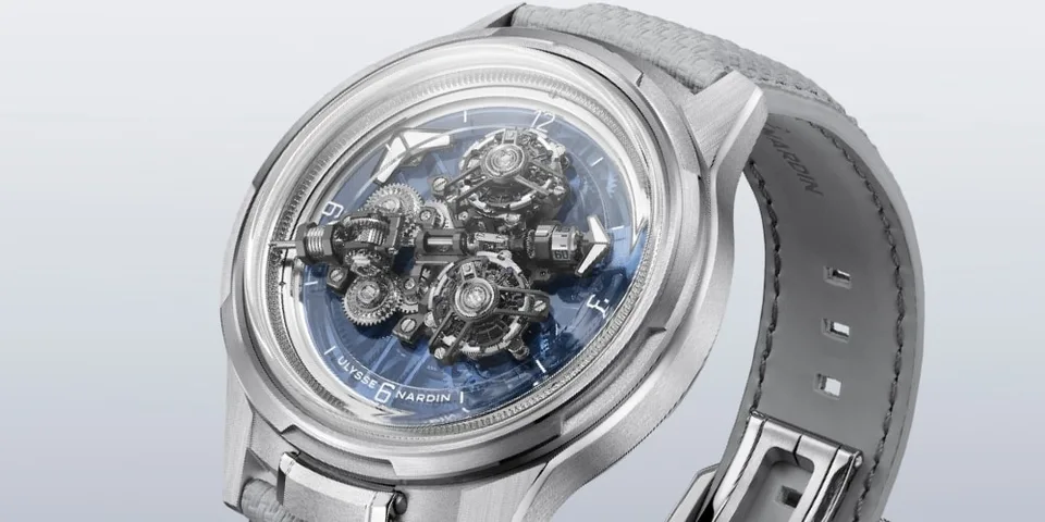 Montre argentée avec mécanisme visible et bracelet en cuir gris