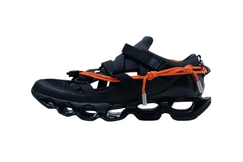Chaussure noire et orange au design innovant avec semelle ajourée.