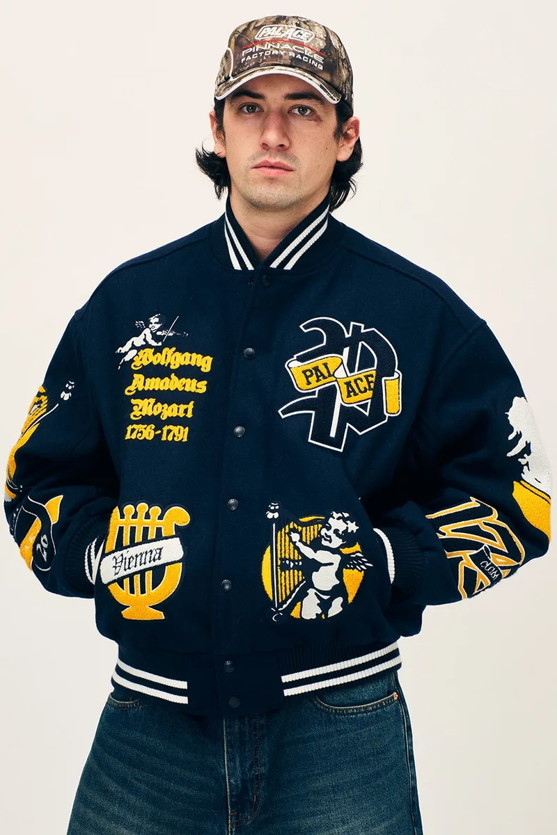 Homme avec une casquette et veste bleu foncé brodée de motifs jaunes.