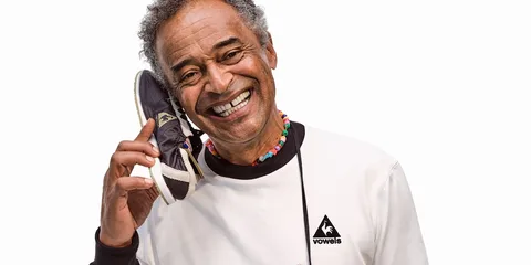 Homme souriant tenant une chaussure contre son oreille.