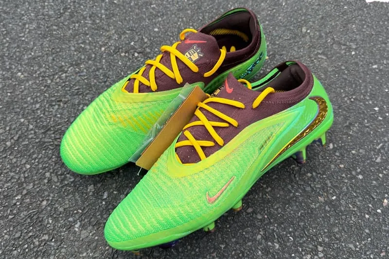 Chaussures de football vertes et marrons avec lacets jaunes, posées sur le sol, vue de dessus.